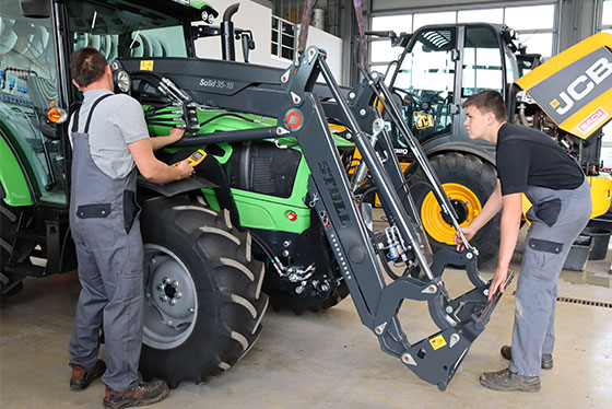 hallenkran aufsatz traktor zwei auszubildende azubis werkstatt halle